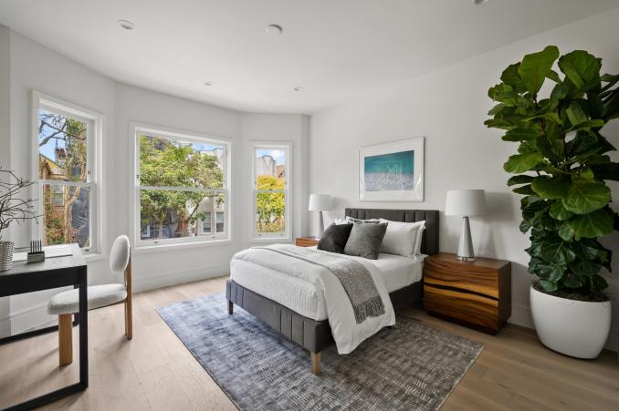 Property Thumbnail: Guest bedroom has queen bed with two bedside tables and a small desk. There are large bay windows. 