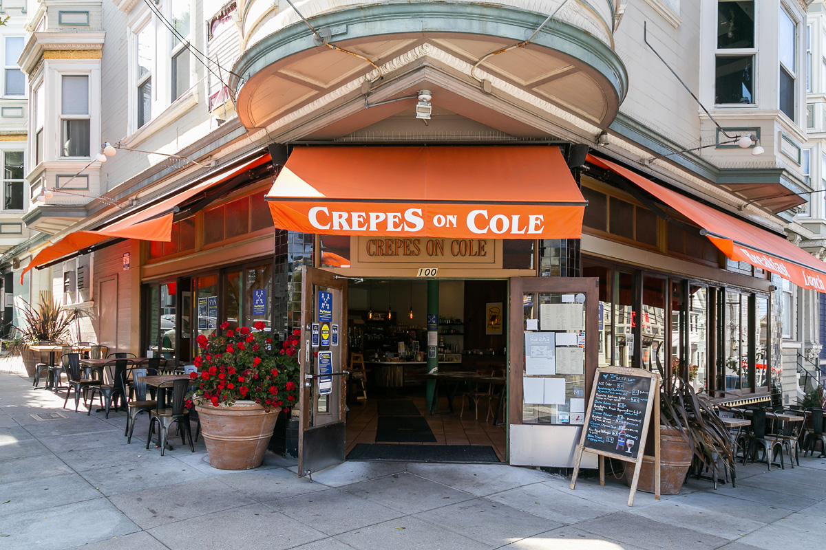 Street view of Crepes on Cole, showing a restaurant with orange awning 