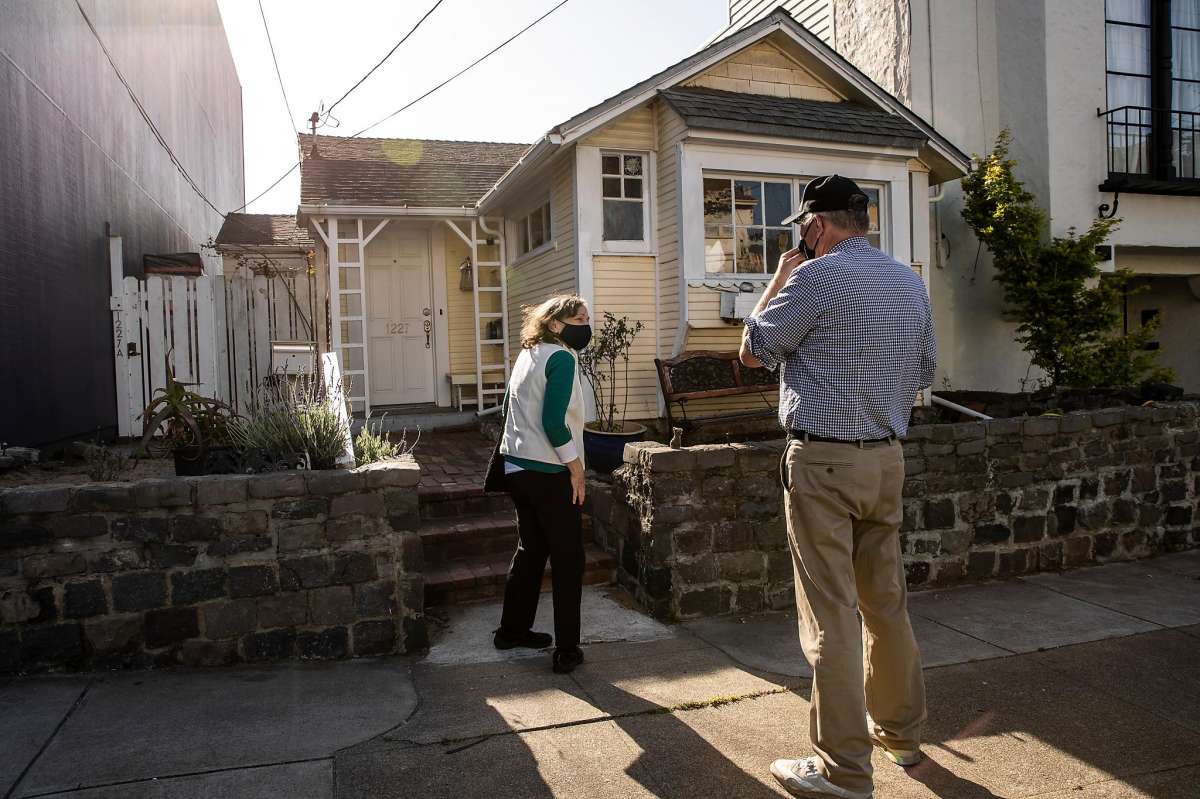 Two people converse outside of a house