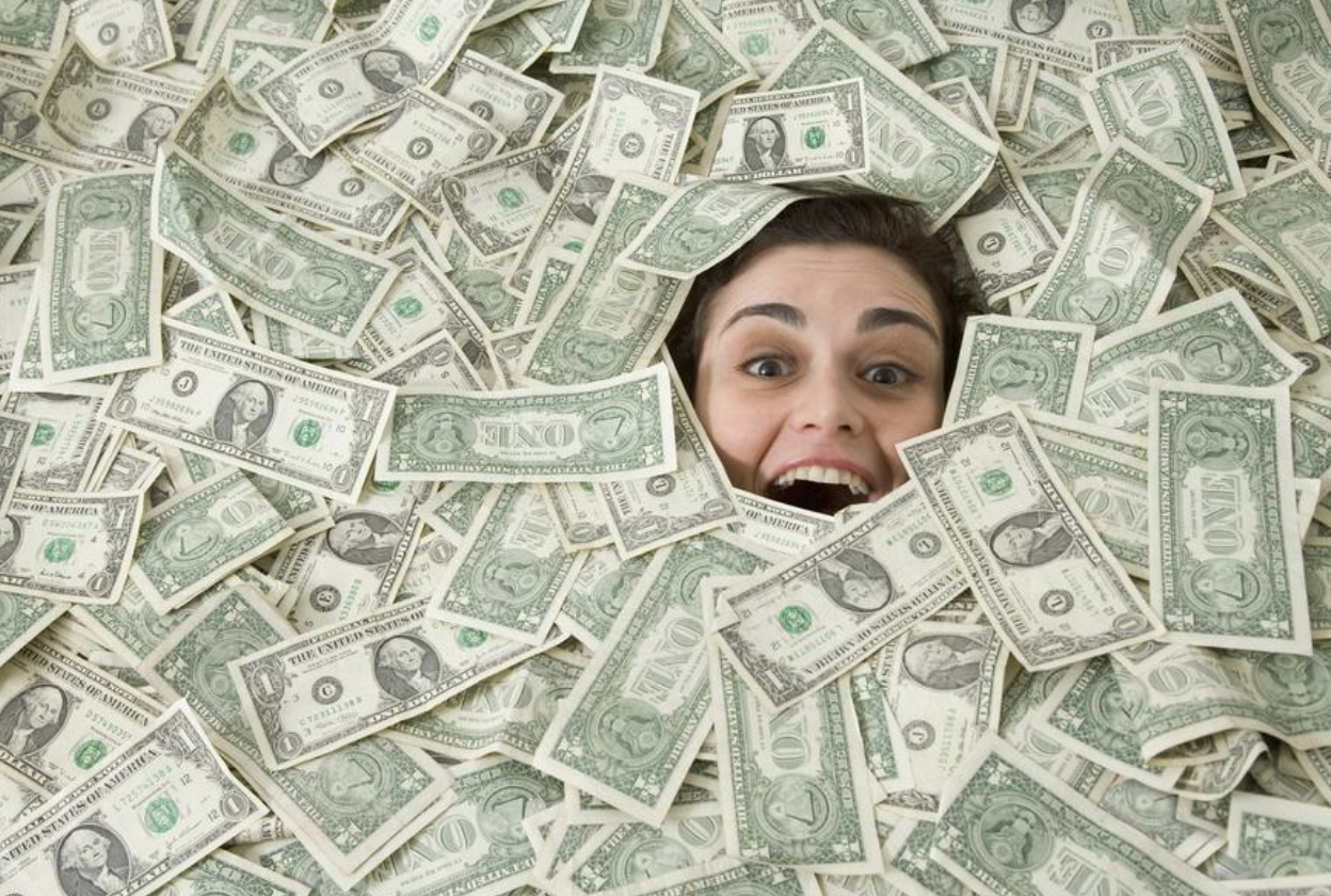 A woman's face is poking through a pile of money