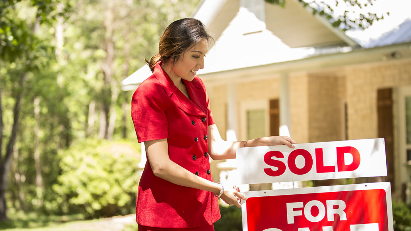 Woman holding a for sale sign
