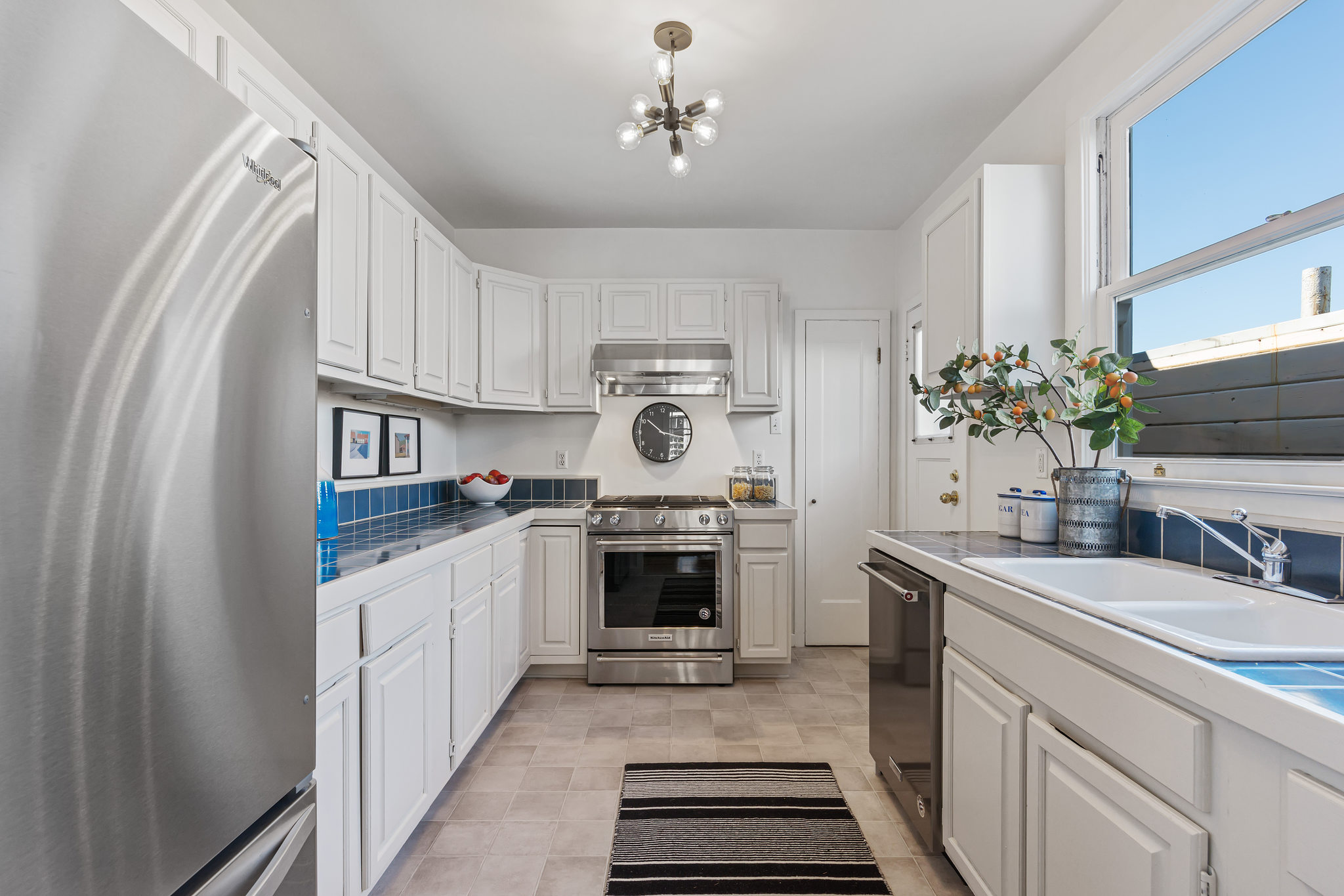 Property Photo: View of the galley-style kitchen, featuring white cabinetry 