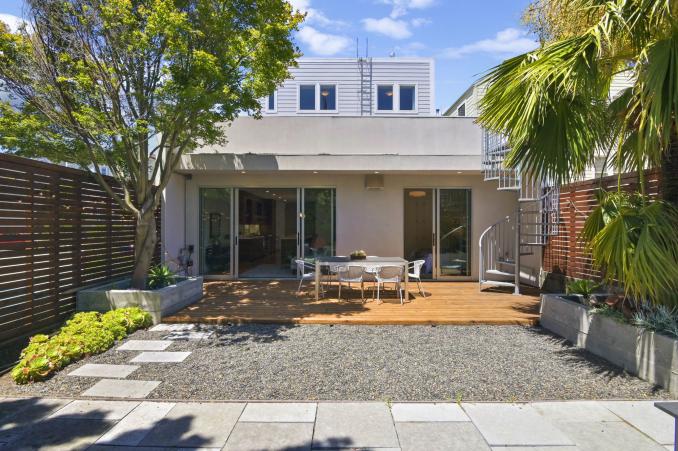 Property Thumbnail: Rear exterior view of the ground-level outdoor space, showing an outdoor living area and palm trees