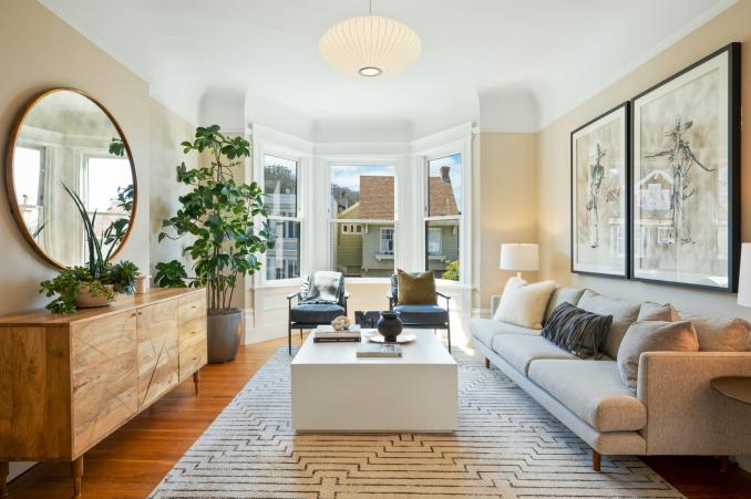 Property Thumbnail: Centered photo of 636, upper unit. Large couch to right with two chairs in front of the bay window. 