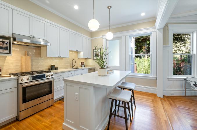 Property Thumbnail: Kitchen has upper and lower white cabinets with light tan glass tile backsplash. Stainless hood above stove. 