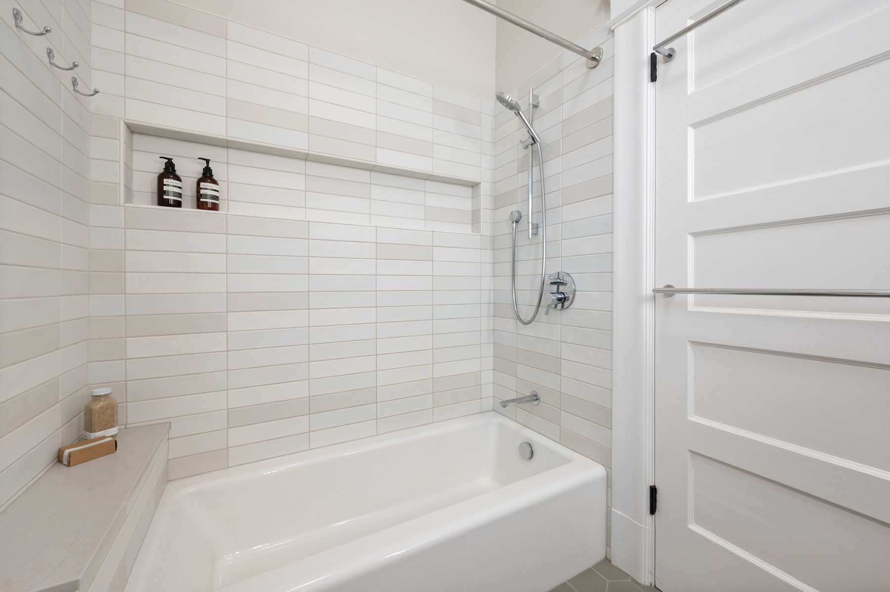 Property Photo: Bathroom has tub/shower combo with light grey and white tile detail. 