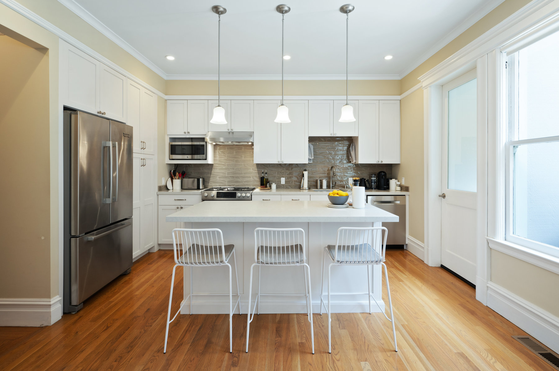 Property Photo: Centered kitchen photo highlighting island that has three stools. 