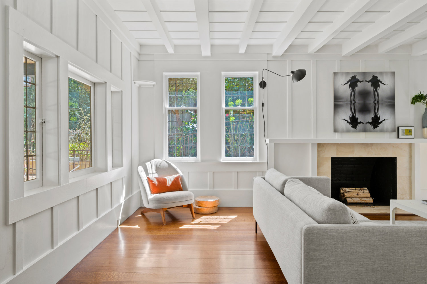 Property Photo: Looking into living room from the entryway. Small chair near windows. 