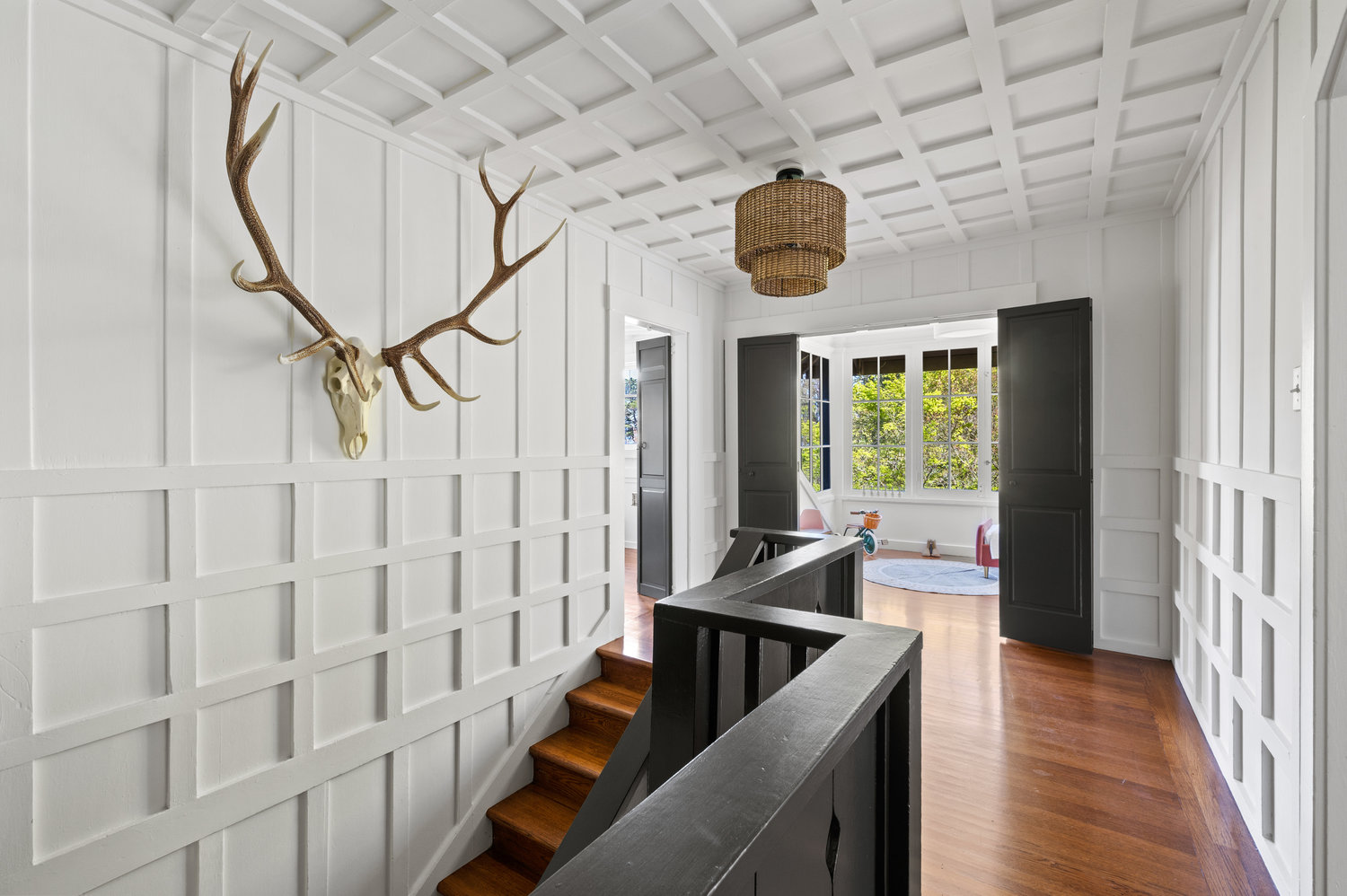 Property Photo: Looking at stairway from upper level. Lots of wood details on walls and ceiling. 