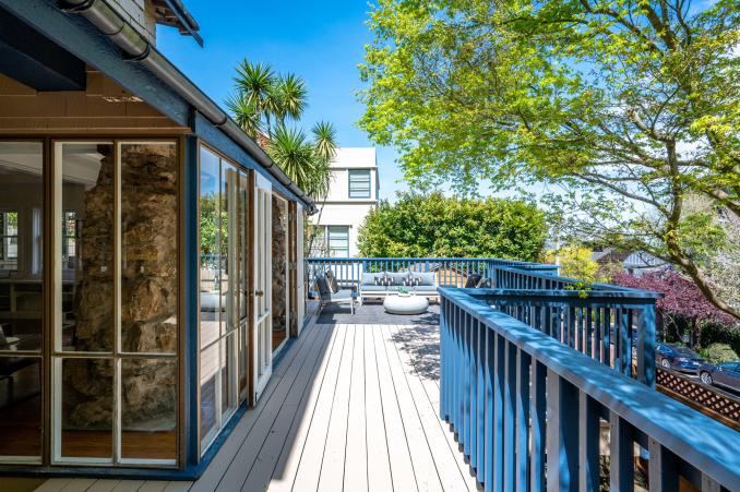 Property Thumbnail: Looking down deck. Light blue railings, and a large seating area. Lots of trees.