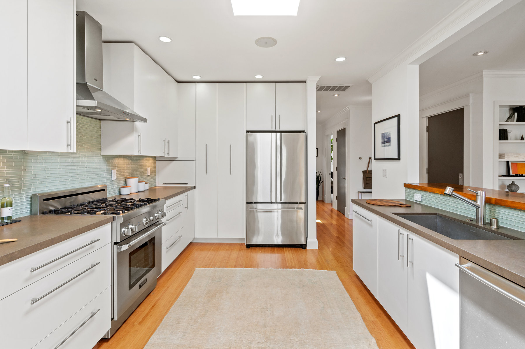 Property Photo: Kitchen from dining room. All stainless steel appliances with all white cabinetry. 