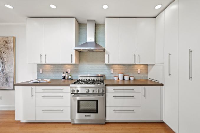 Property Thumbnail: Photo with kitchen stove centered. Stove has matching stainless hood. There are upper and lower cabinets on both sides of stove. 