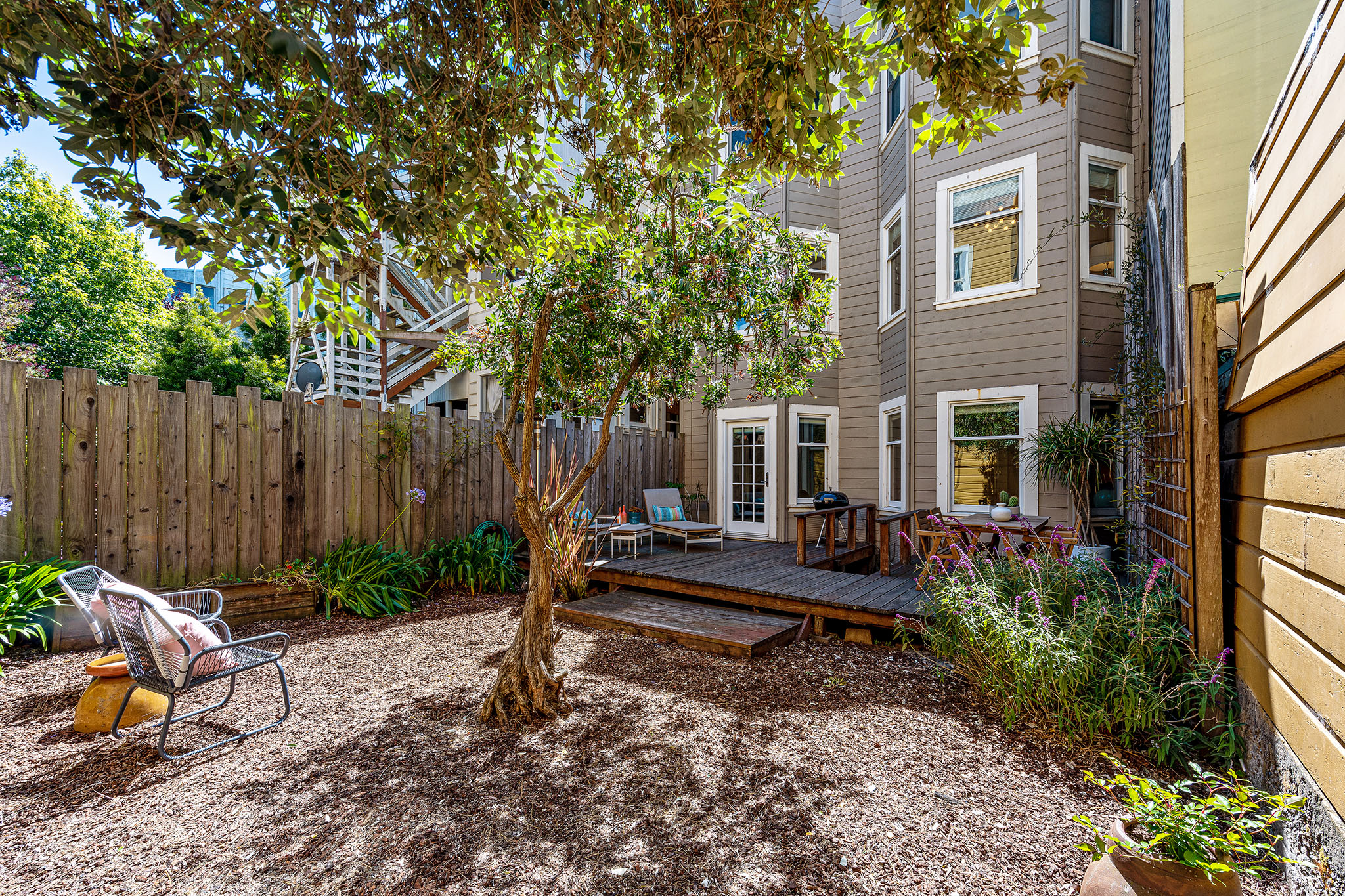 Property Photo: View of the rear yard, featuring trees and an outdoor seating area