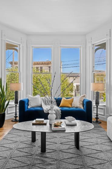 Property Thumbnail: Close up photo of blue couch in front of large bay windows. 