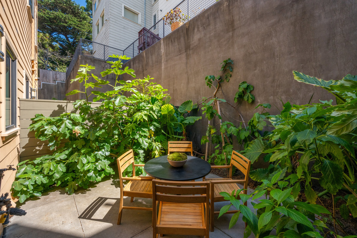 Property Photo: Back patio has round dining table and lots of lush tropical plants that add a lot of greenery. 