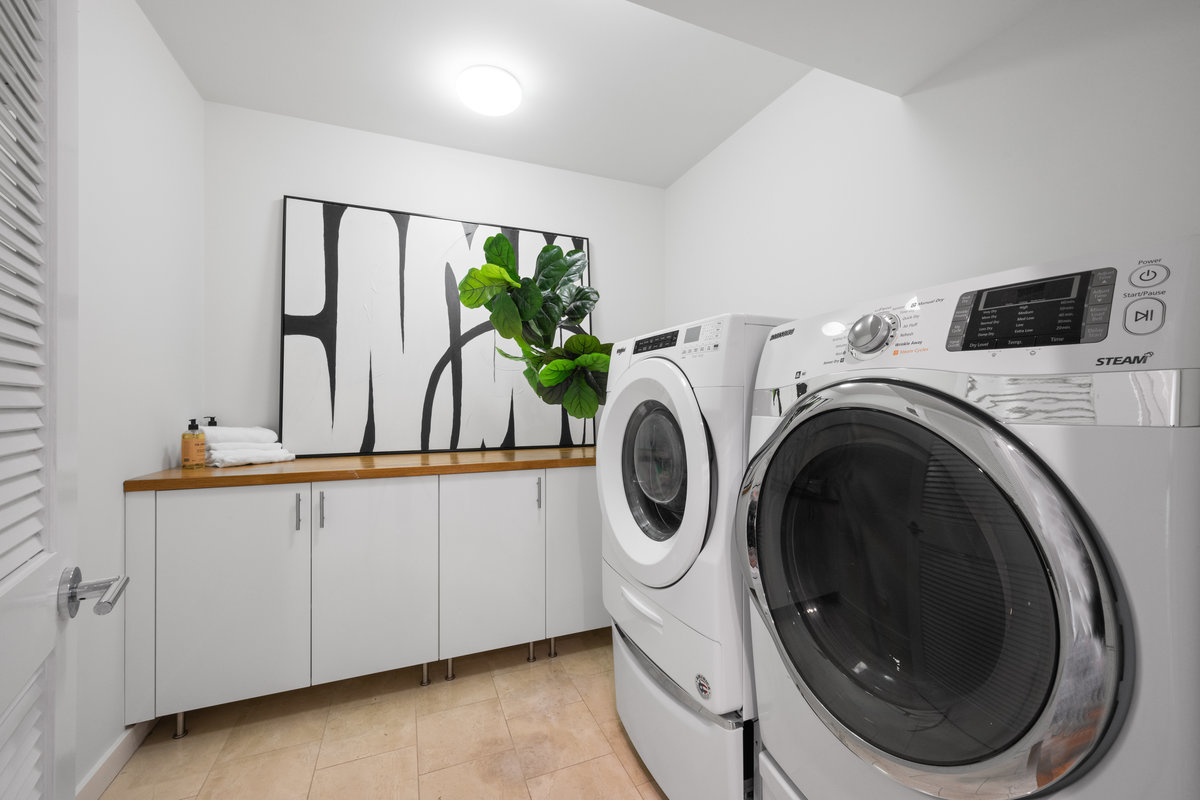 Property Photo: Laundry room has built in lower cabinets with wooden countertop and large side by side washer and dryer.