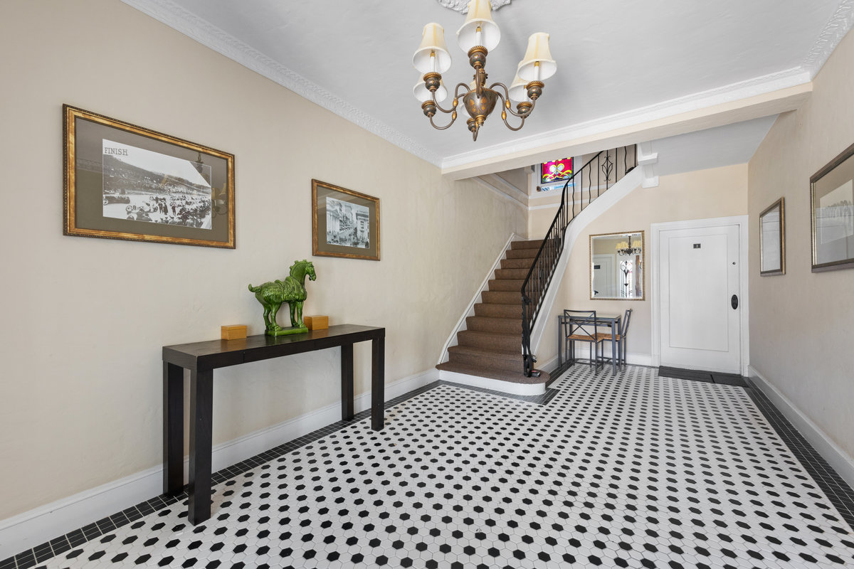 Property Photo: Entrance to the building had black and white tile floors and cream walls. Stairway to upper units is to the left. 