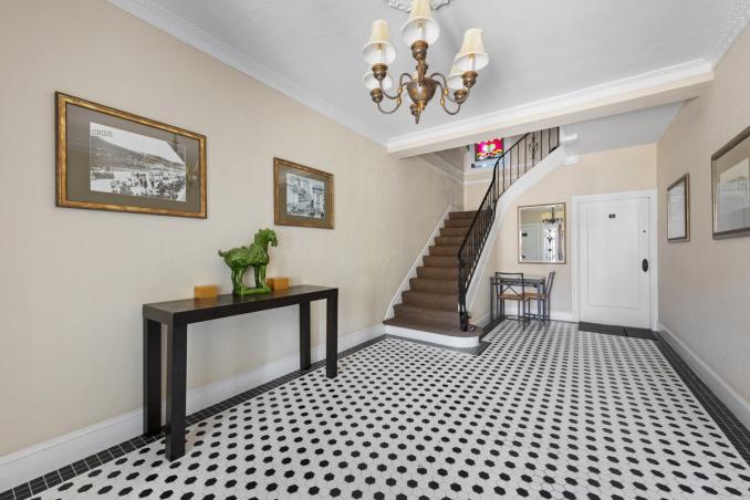 Property Thumbnail: Entrance to the building had black and white tile floors and cream walls. Stairway to upper units is to the left. 