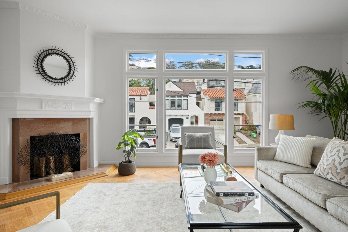 Property Photo: Looking over living straight at front windows. Fireplace is in the corner to the left. Original harwood floors through out room. 