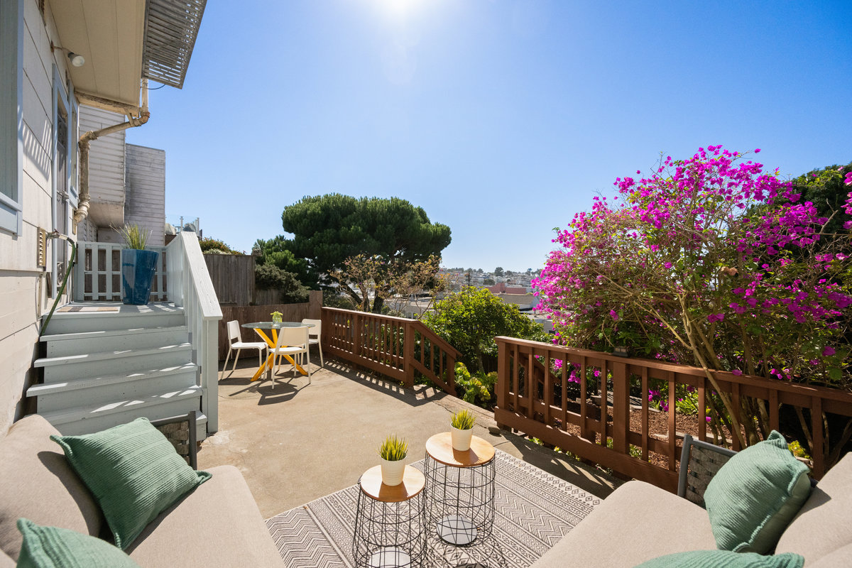 Property Photo: There is a sitting area on the upper part of the yard near home. There is L shaped lounge couch and another small table with chairs on the other side 