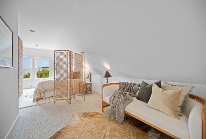 Property Thumbnail: The upper level has a large space that is staged as a sitting area and bedroom. There are vaulted ceilings. 