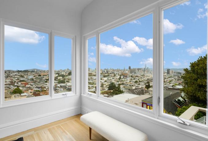 Property Thumbnail: There is a small bench in front of the large windows in the dining room. There are hardwood floors throughout. 