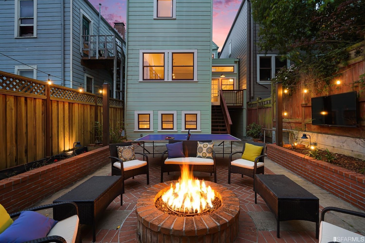 Property Photo: Rear exterior view showing an outdoor fireplace and seating
