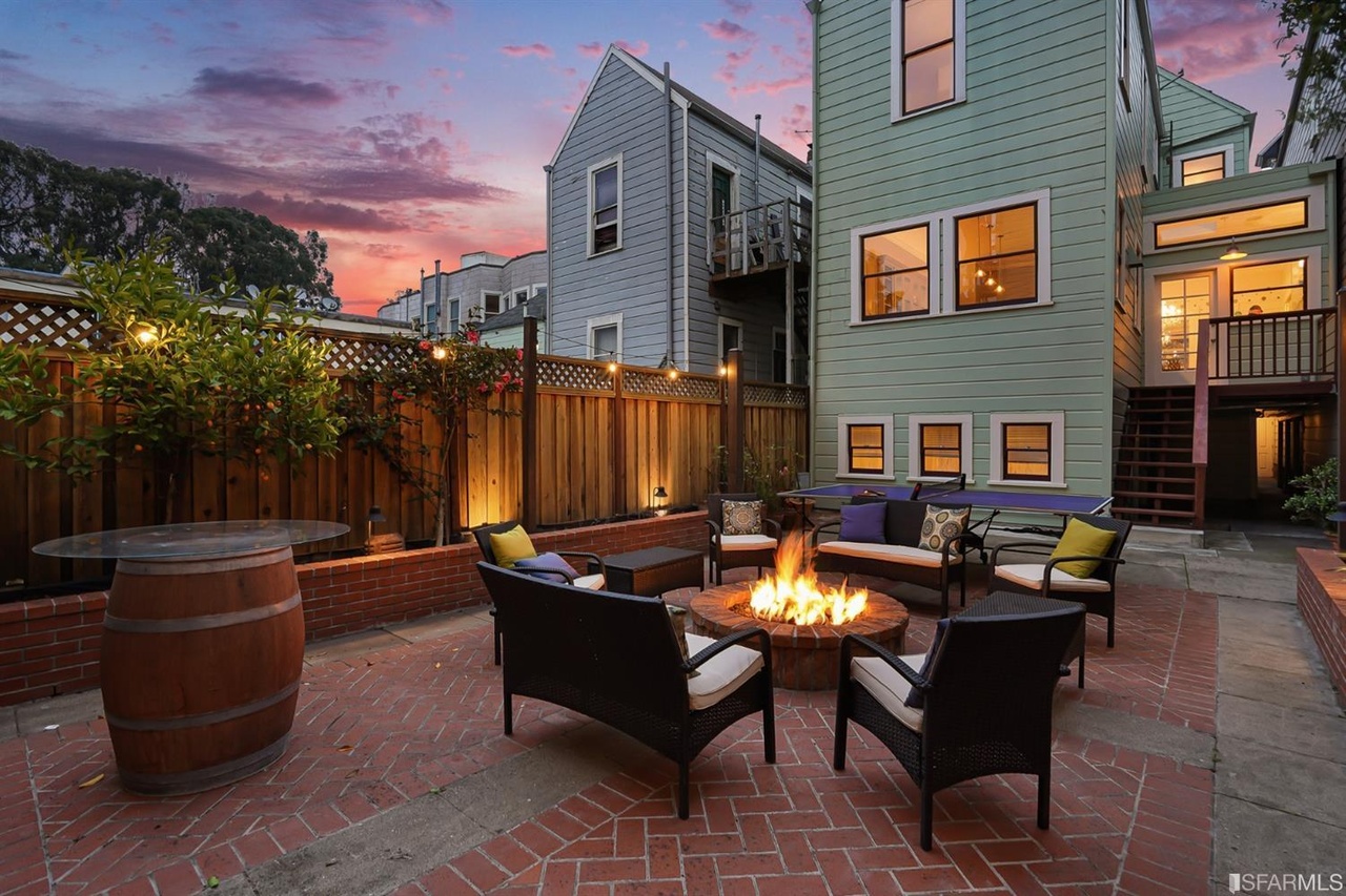 Property Photo: View of the patio at twilight, featuring a fire in the outdoor fireplace 