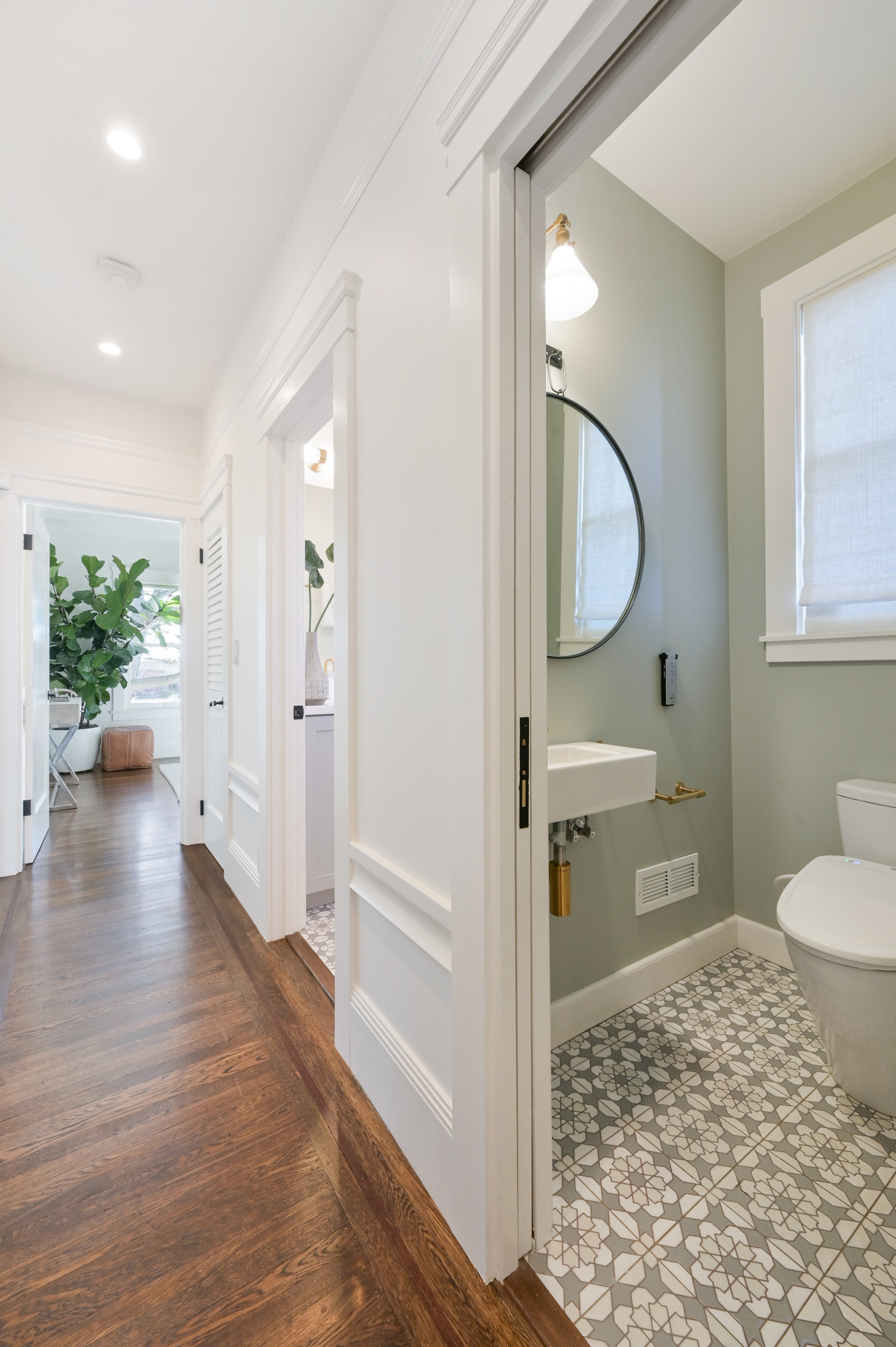 Property Photo: Partial view of the hallway with wood floors and a bathroom