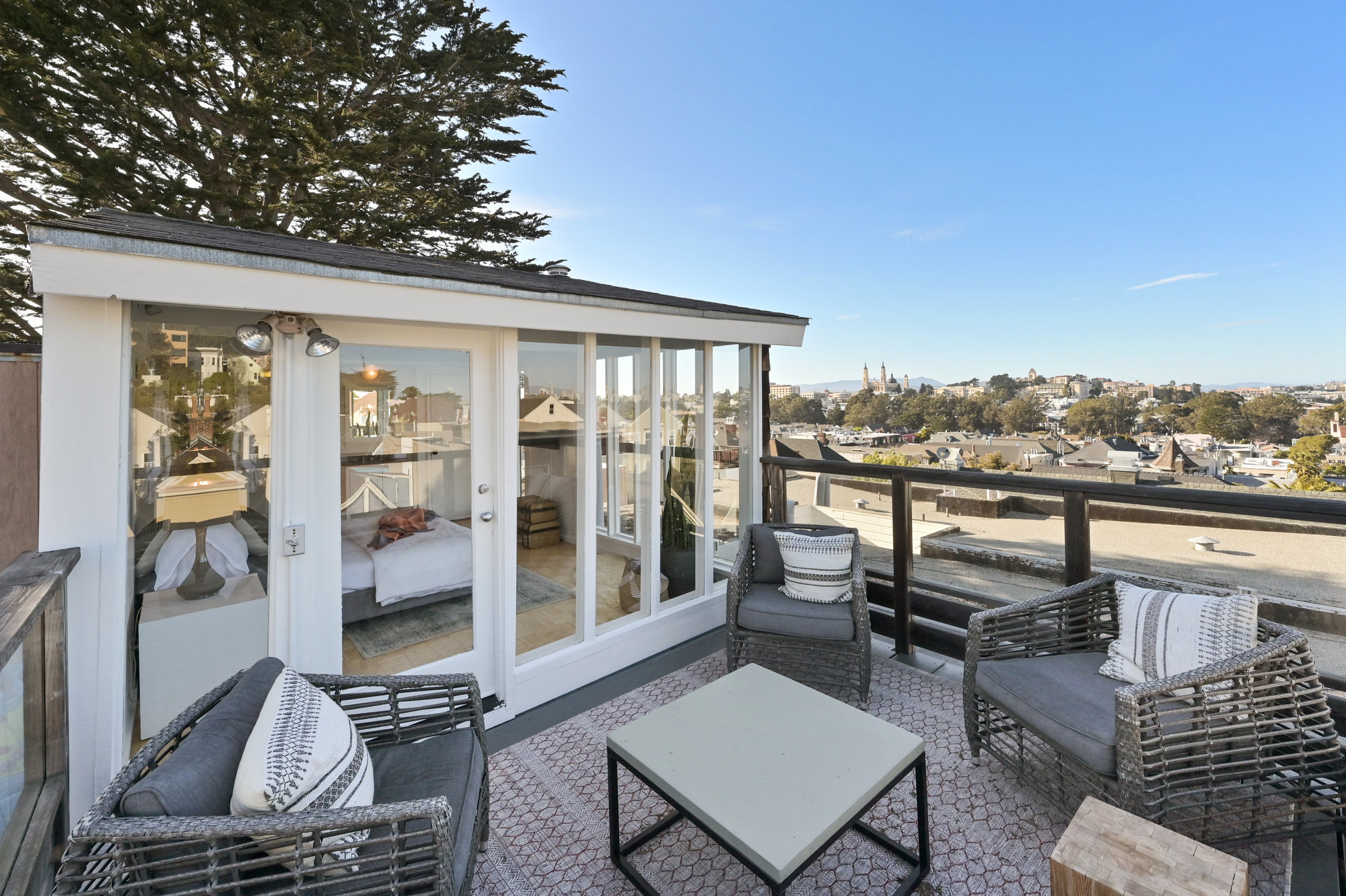 Property Photo: A view of the third bedroom from the rooftop deck, showing a glass framed bedroom with the city in the background