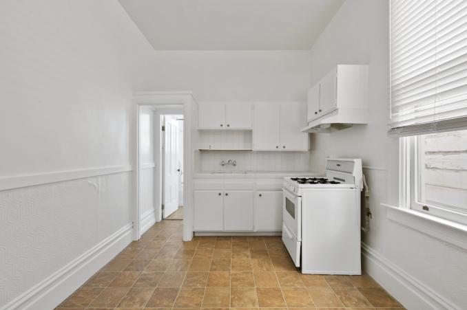 Property Thumbnail: Kitchen with white cabinets, showing a stove and window