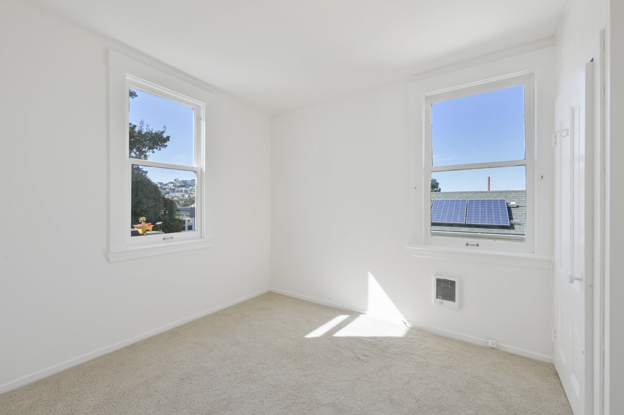 Property Photo: View of a bedroom with two windows and outlooks of the city 