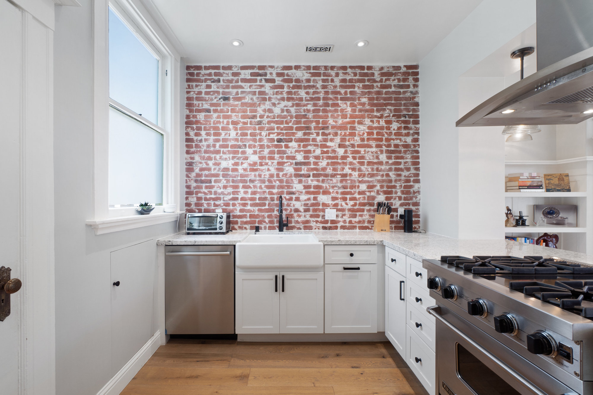 Property Photo: Kitchen with exposed brick wall, showing a farmhouse sink