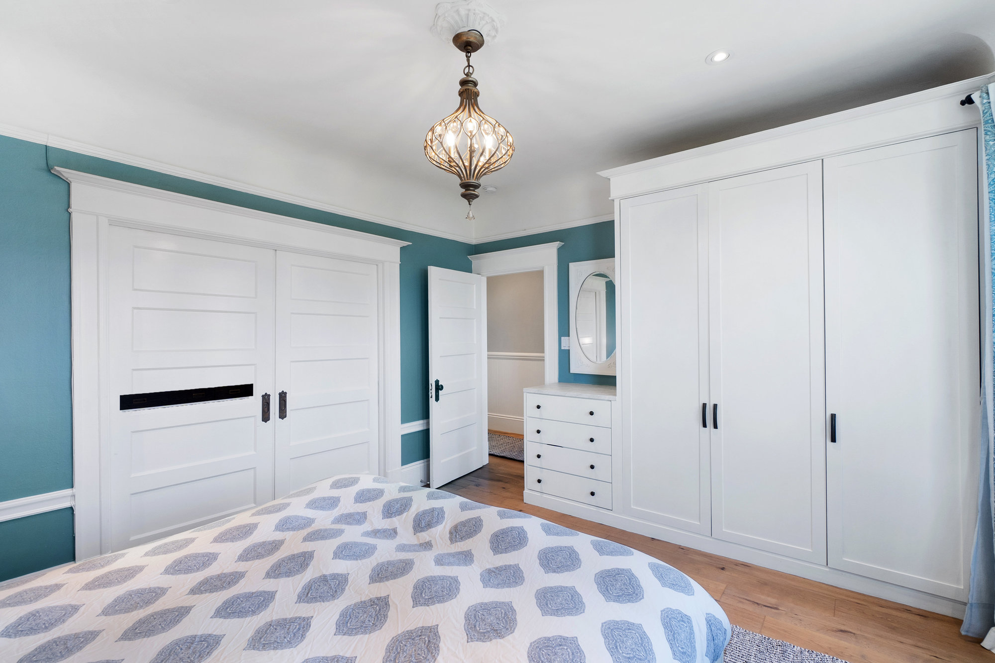 Property Photo: Primary bedroom with white wood closets and a chandelier 