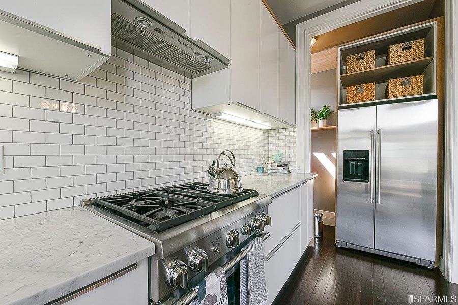 Property Photo: View of a kitchen, featuring white tile backsplash and stainless appliances