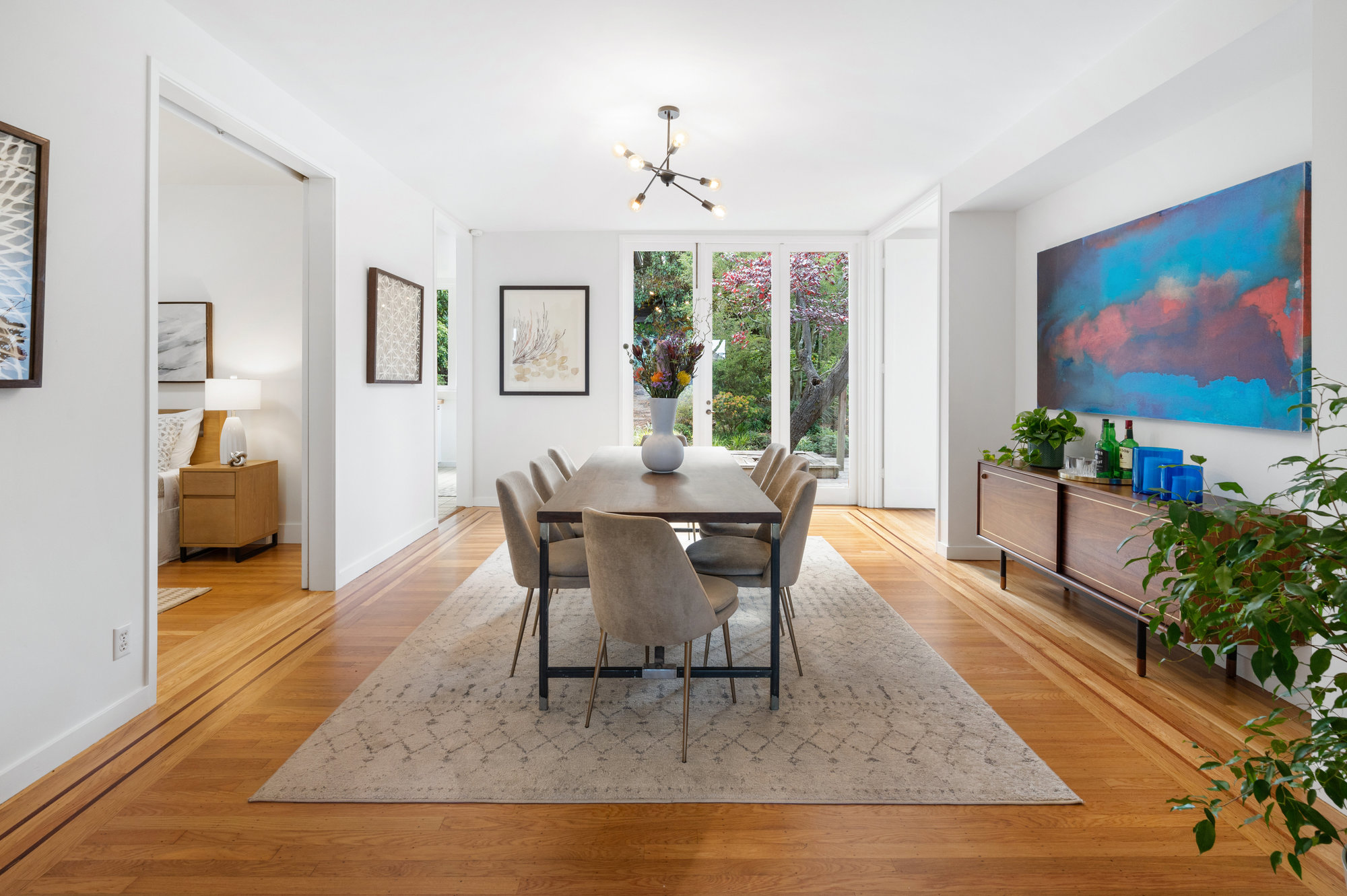 Property Photo: Long-view of the formal dining room, featuring modern lighting and wood floors