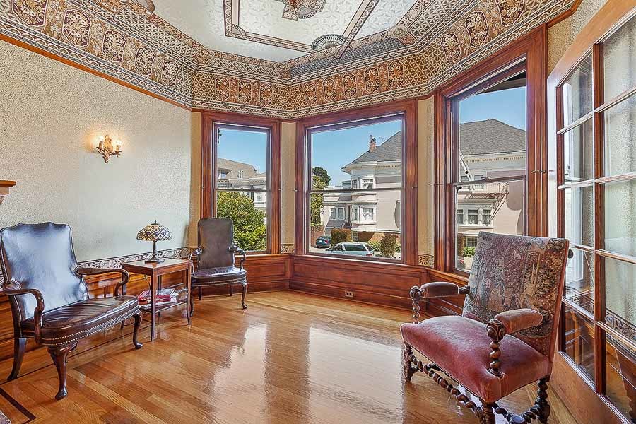 Property Photo: View of a formal living room, with wood floors , three large windows, and an ornate ceiling 