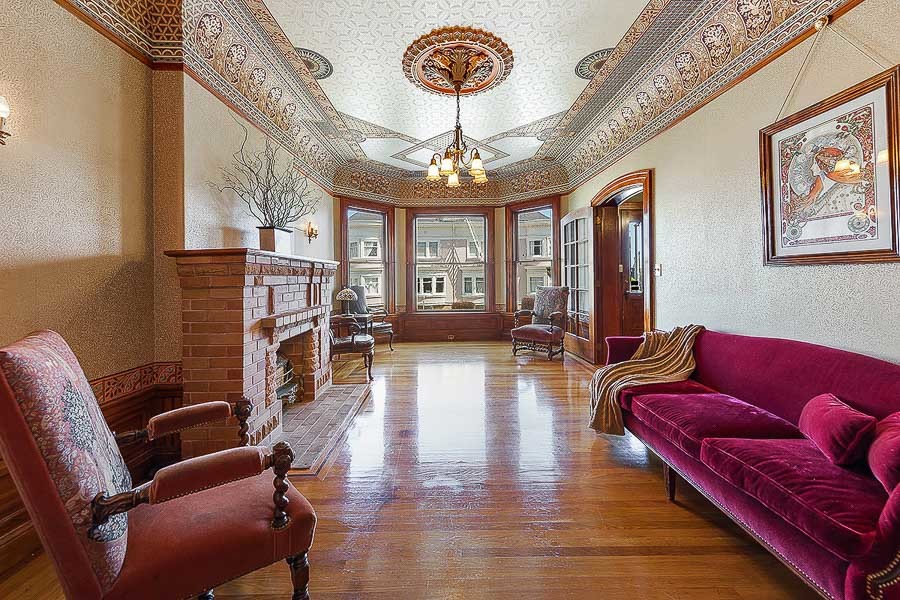 Property Photo: Long view of a formal living room, featuring a fireplace and ornate crown moulding 