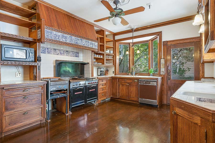 Property Photo: View of the kitchen, featuring wood cabinets, wood floors, a large window and high-end appliances