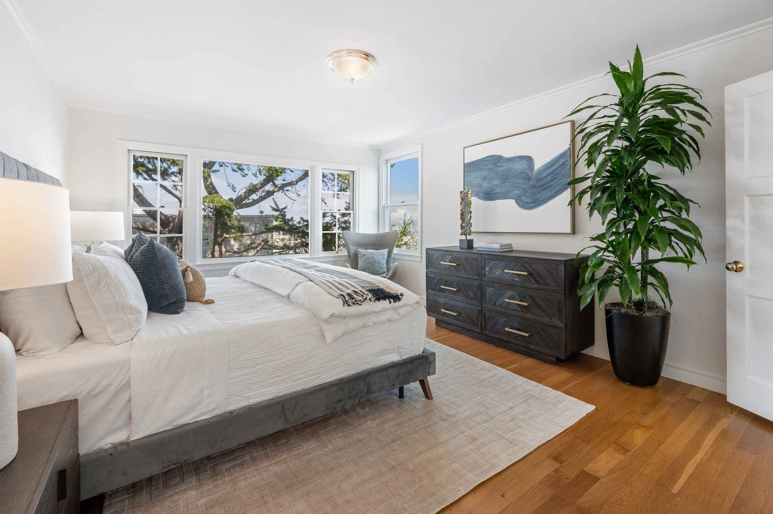 Property Photo: Primary bedroom with large windows and wood floors