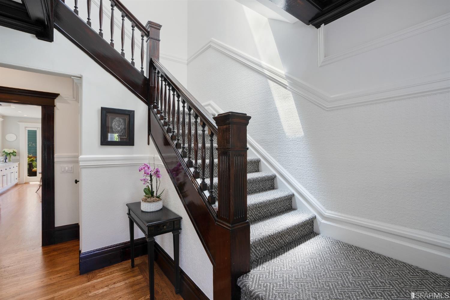 Property Photo: A large staircase with elegantly crafted railing lead to the second story of the home