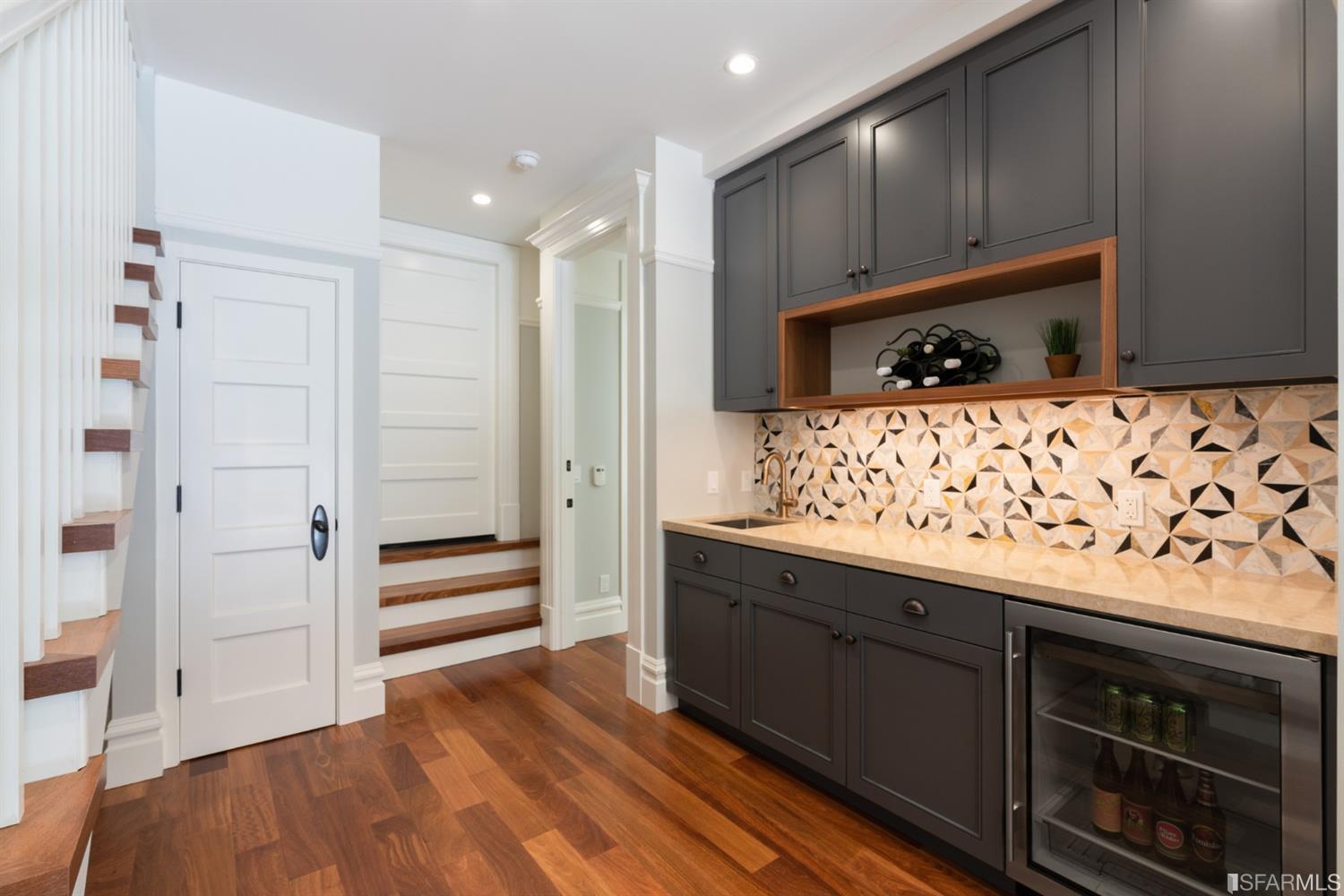 Property Photo: View of the lower kitchen or bar area, featuring a beverage cooler and cabinetry