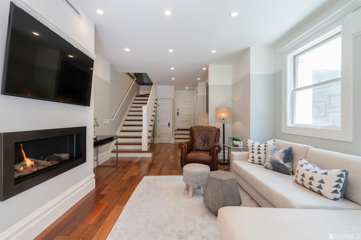 Property Photo: View of the lower living area, featuring a modern gas fireplace and wood floors
