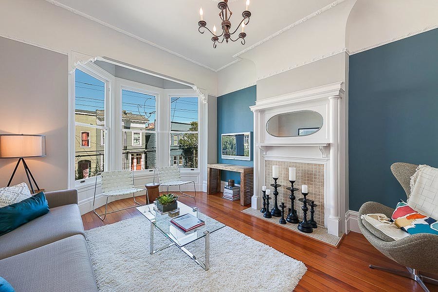 Property Photo: Living room with fireplace mantle and three large windows