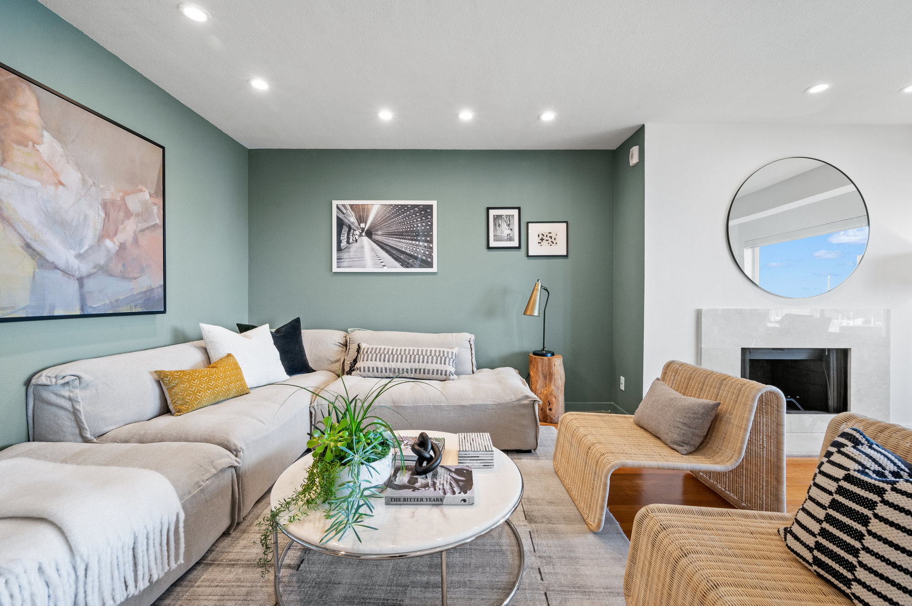 Living room area has pretty light green statement walls. L shaped couch with oval coffee table and two sitting chairs.