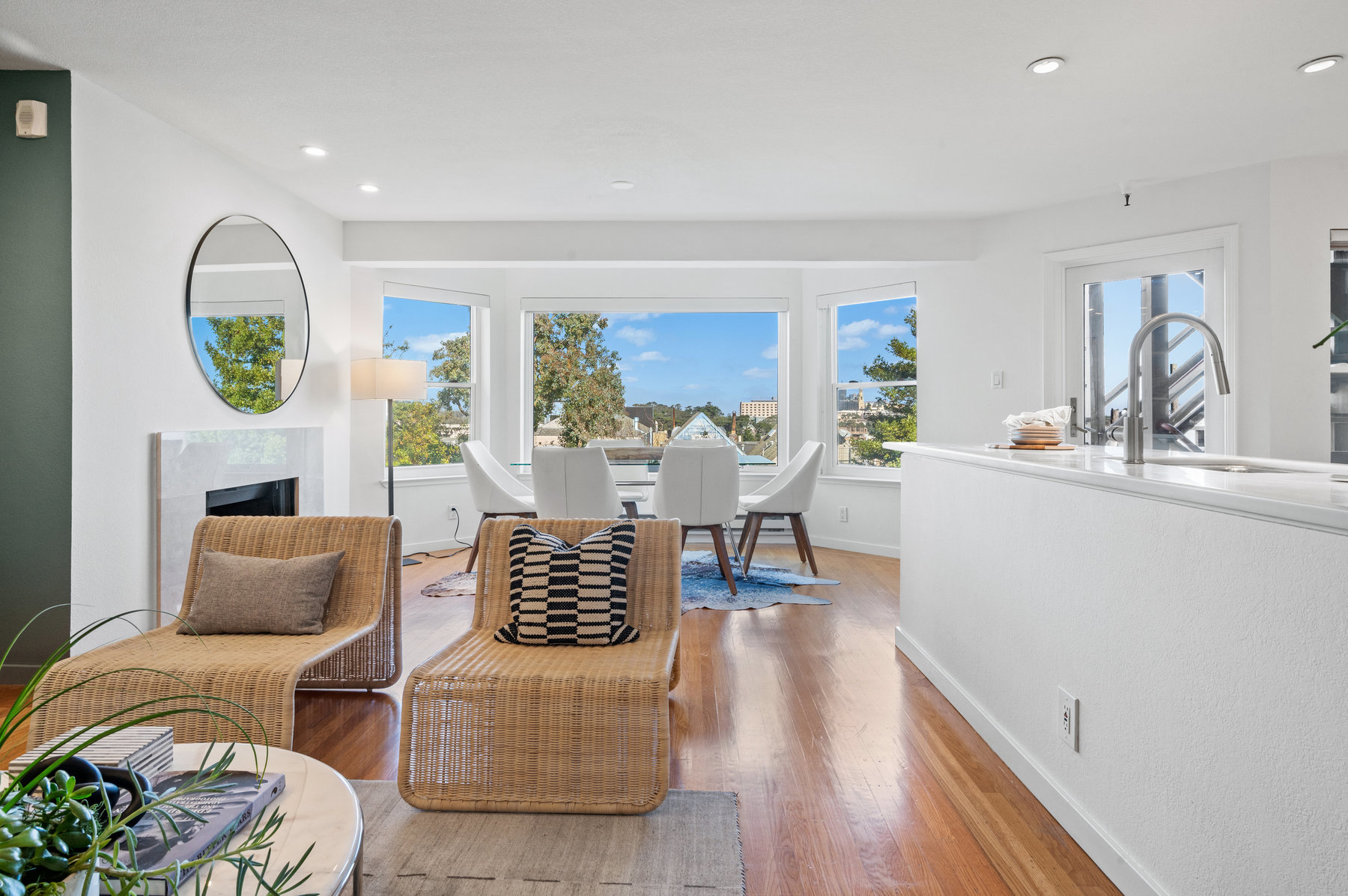 Looking from living room space to dining space. Table is framed beautifully in bay windows.