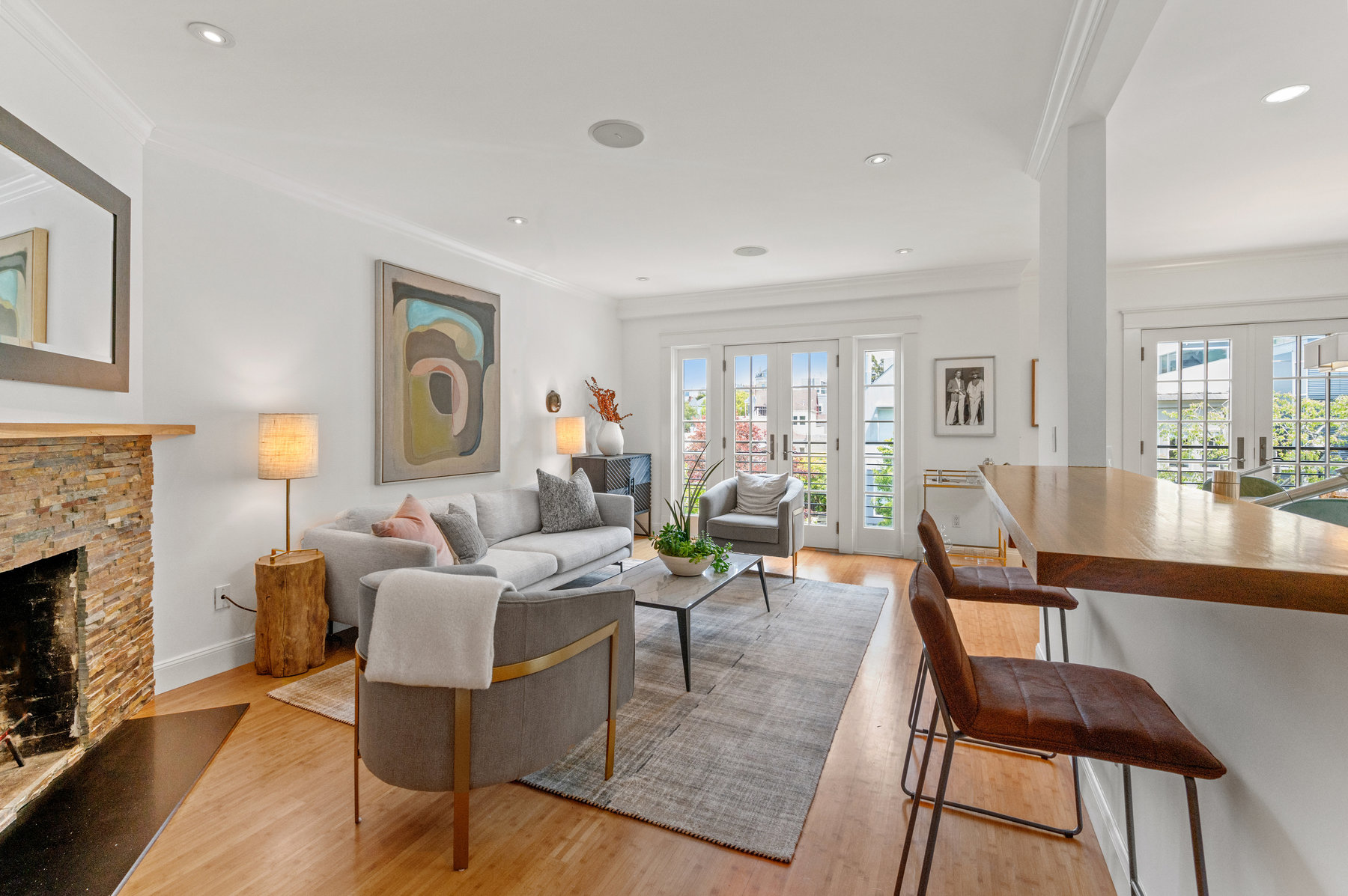 Living room area has couch with two end tables and two plush chairs. Fireplace to the left.