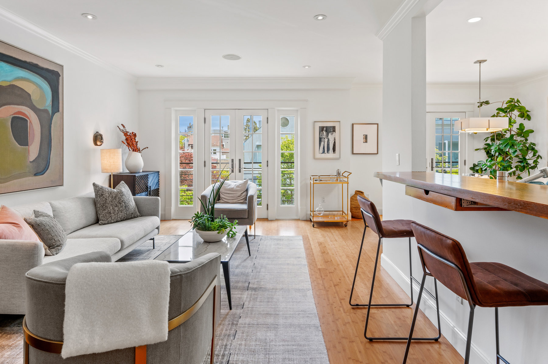 Looking over main living space from entryway. There is a small bar sitting are to the right and sitting area with couch to the left.