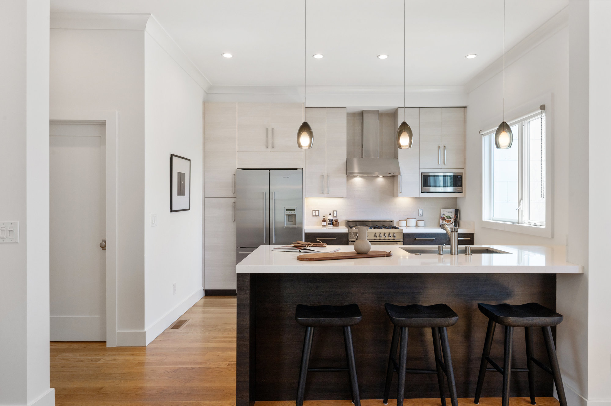 View of the kitchen island with seating, showing pendant lights above