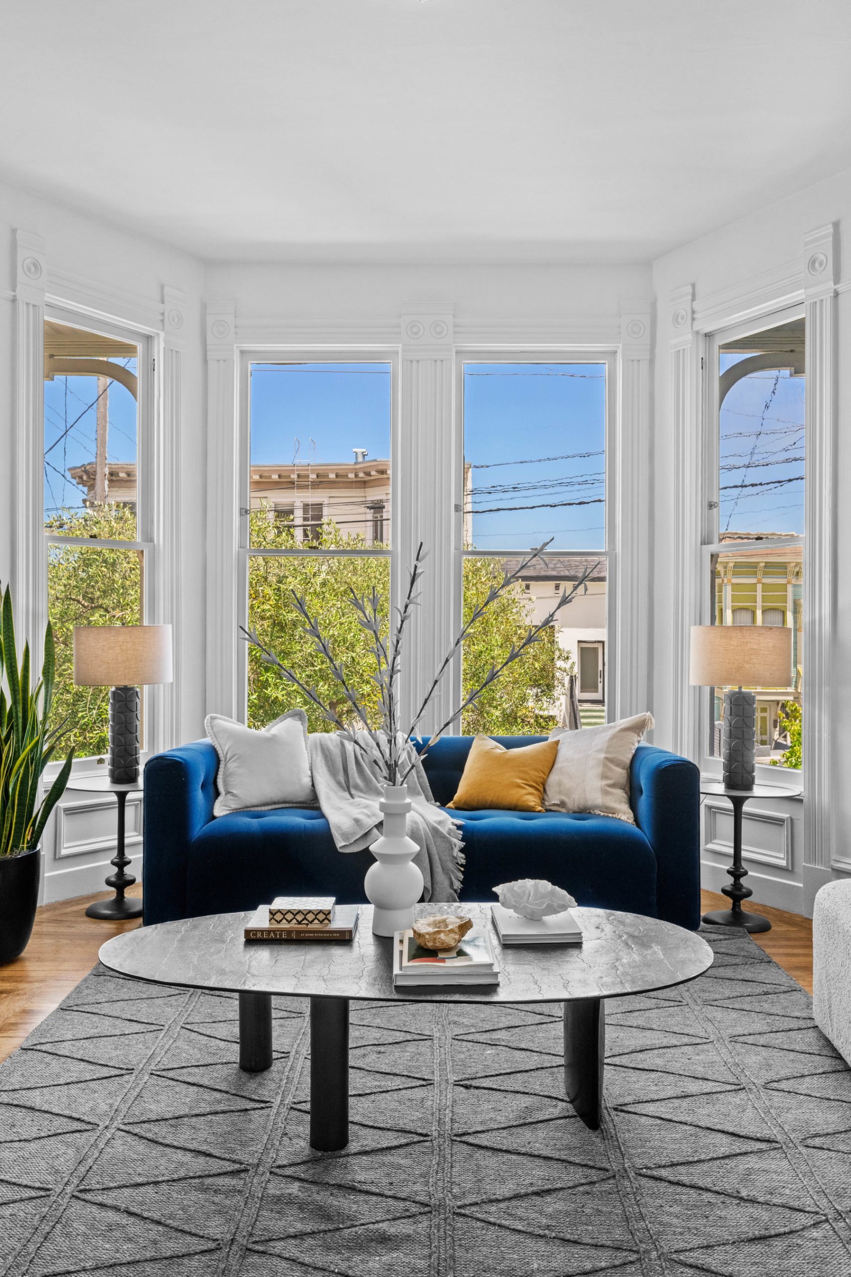 014photos1604castro014146 Close up photo of blue couch in front of large bay windows.